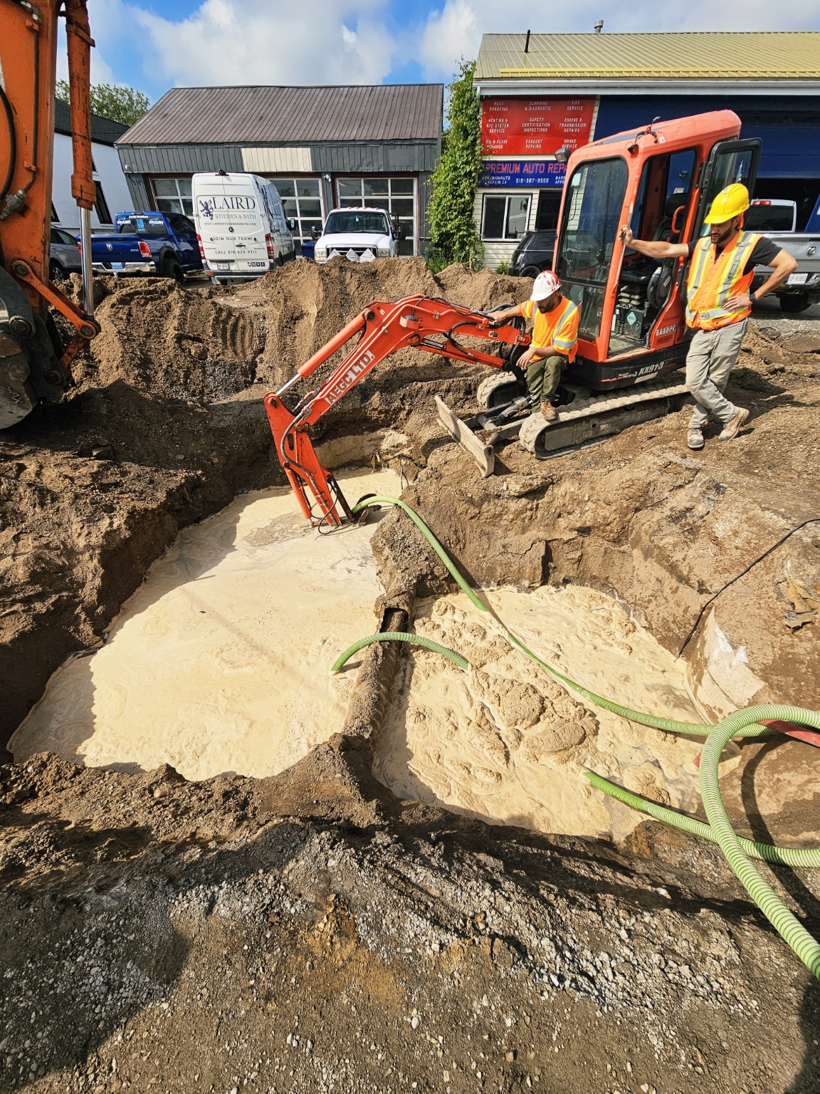 Active utility excavation with exposed services, dewatering and field conditions documented during delivery